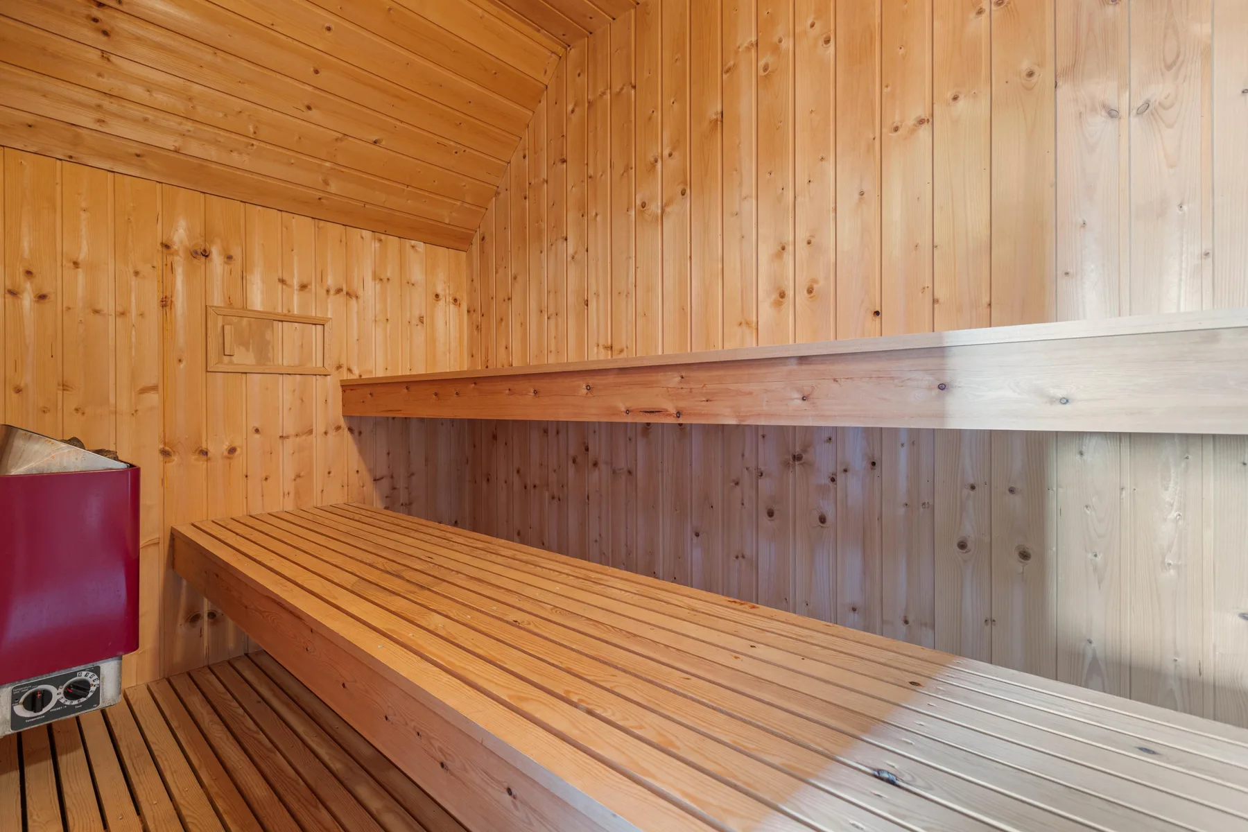 Una sauna de madera con bancos escalonados y un calentador.