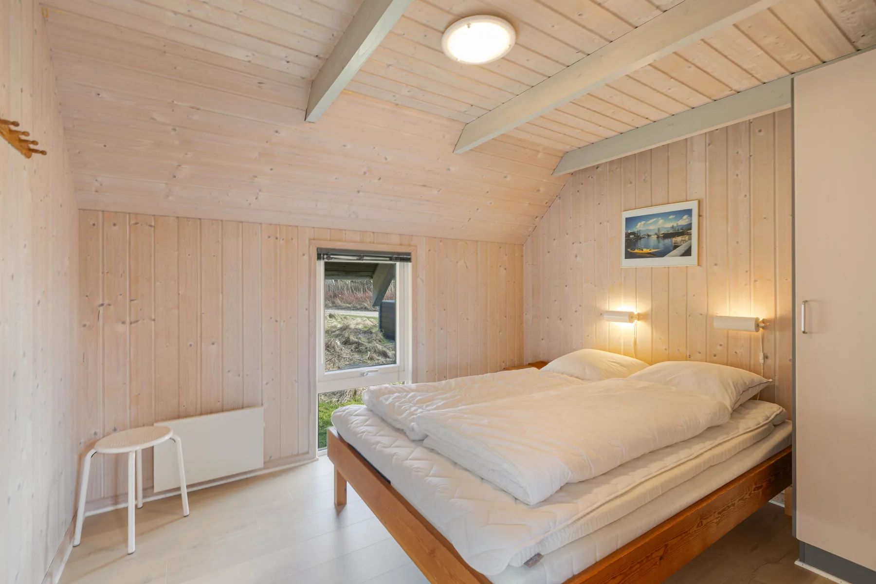 Un dormitorio con una cama bajo un techo de madera inclinado.