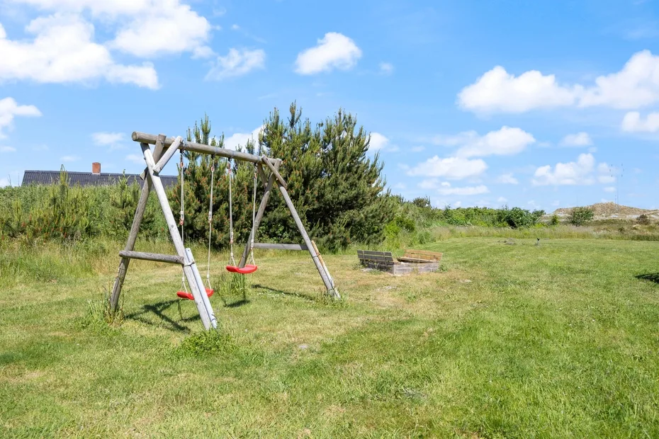 Una zona de juegos al aire libre con columpios de madera y cielo abierto.