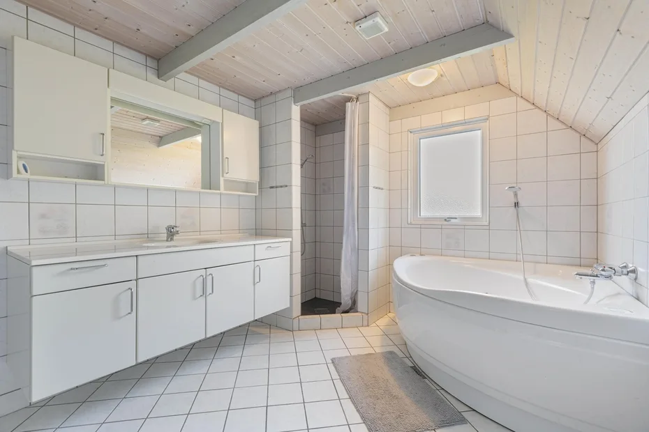 Baño alicatado con bañera, tocador y ducha con cortina.