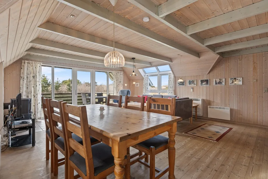 Comedor con una gran mesa de madera y ventanas con vistas al exterior.
