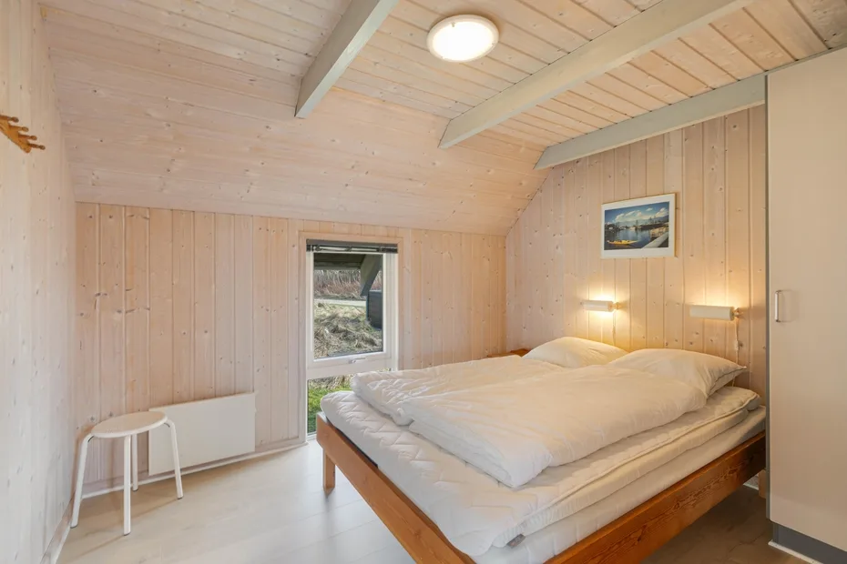 Un dormitorio con una cama grande bajo un techo inclinado revestido de madera.