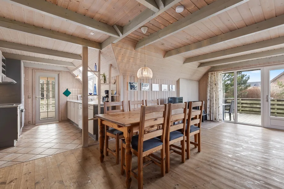 Un comedor con una mesa y sillas de madera junto a una cocina luminosa.