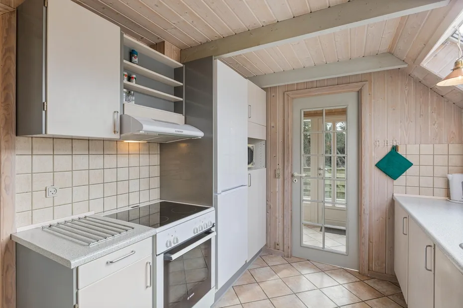 Una cocina compacta con electrodomésticos integrados y una puerta acristalada.