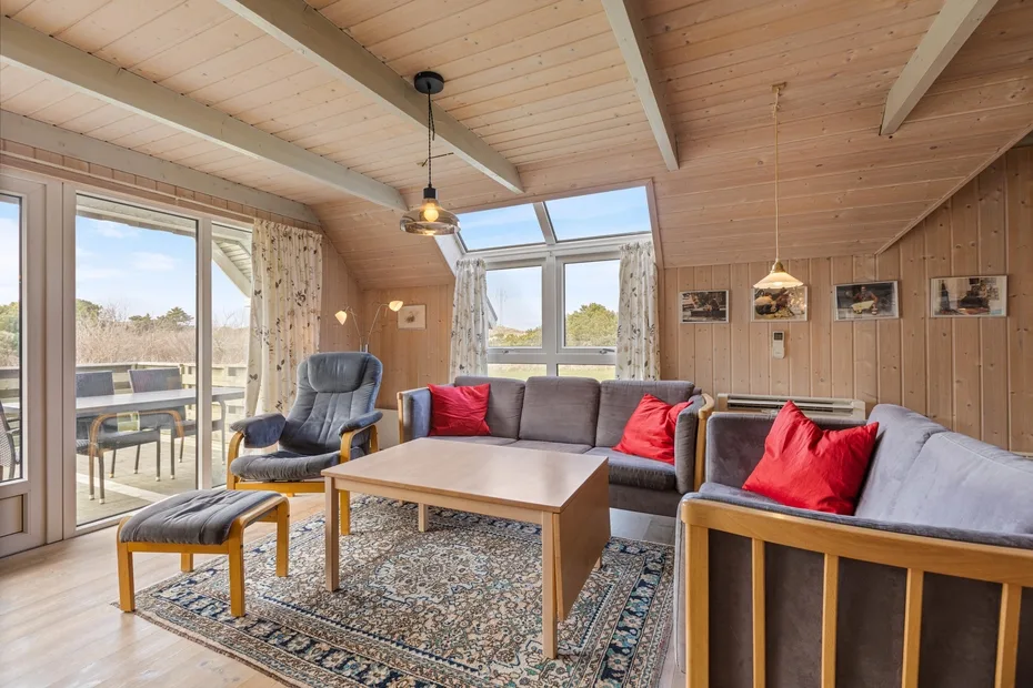 A wood-paneled living room with seating around a coffee table and large windows.