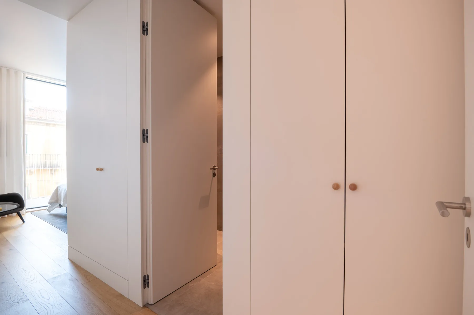 A hallway with open doors and built-in closets.