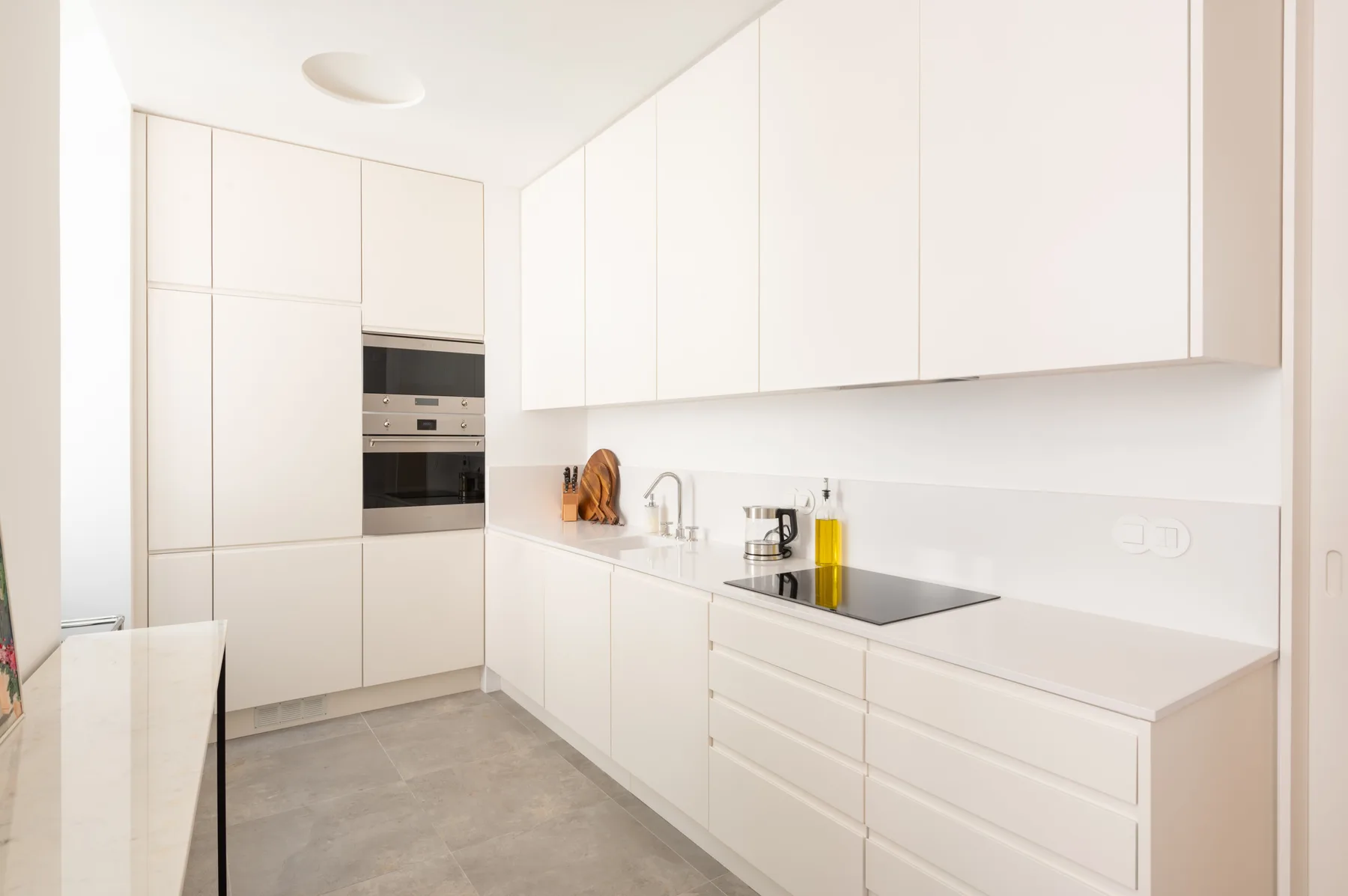 A bright modern kitchen with white cabinets and a built-in oven.