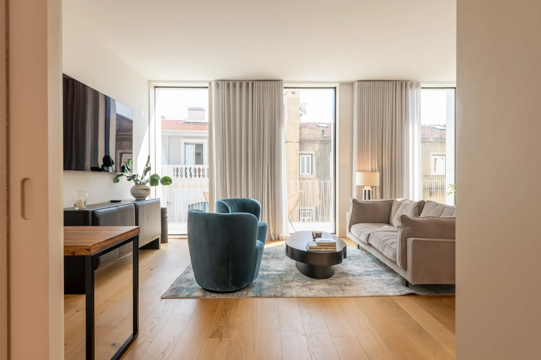 A bright living room with seating arranged around a coffee table beside large windows.