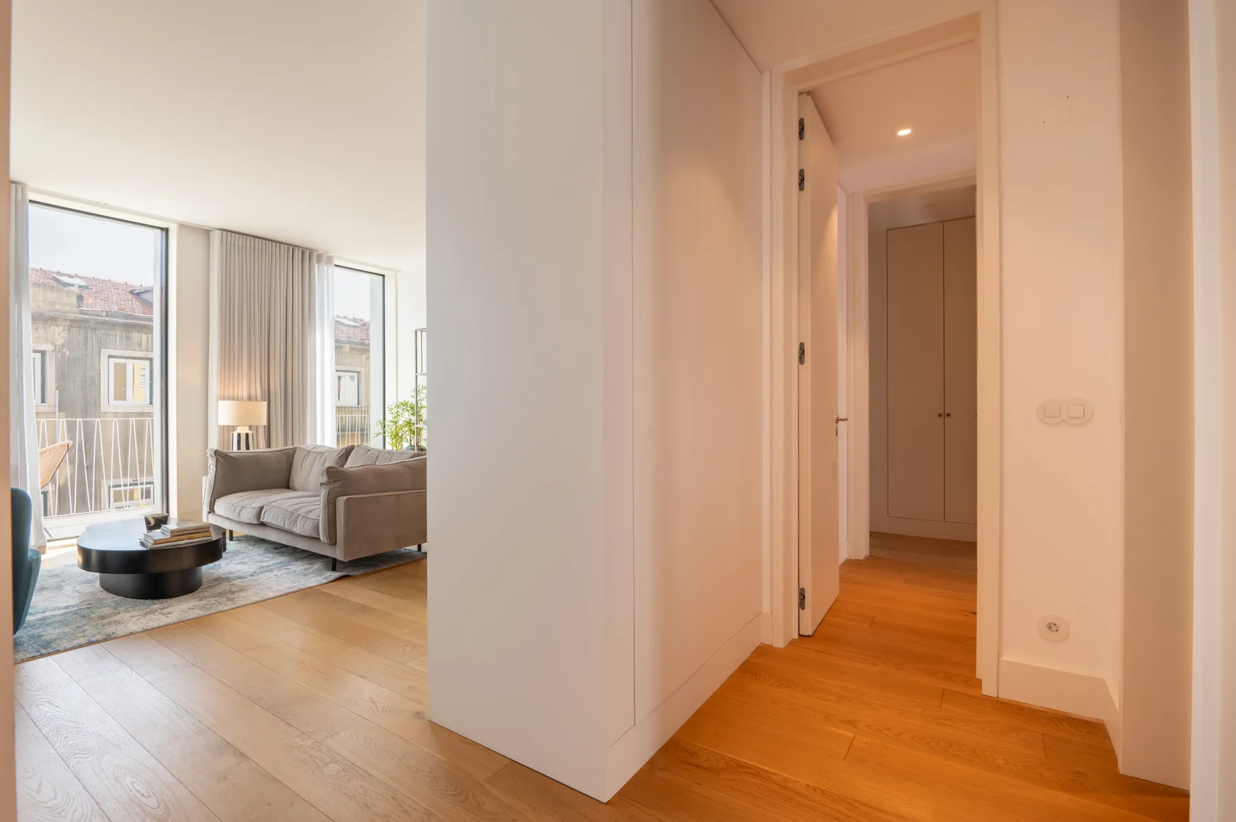 A bright living area with seating beside a hallway.