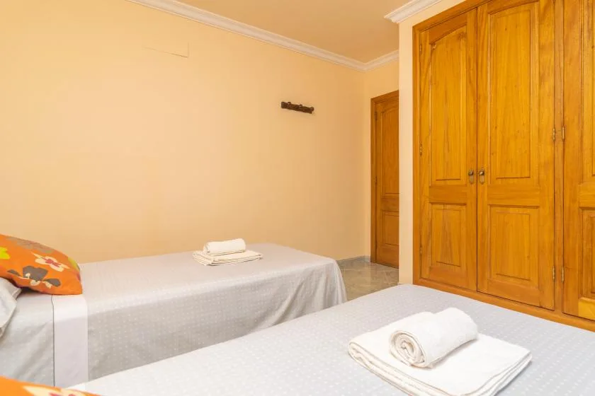 Un dormitorio con dos camas y armarios de madera junto a la pared.