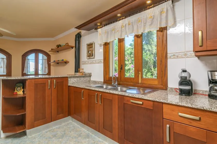 Una cocina con armarios de madera y una encimera bajo una ventana.