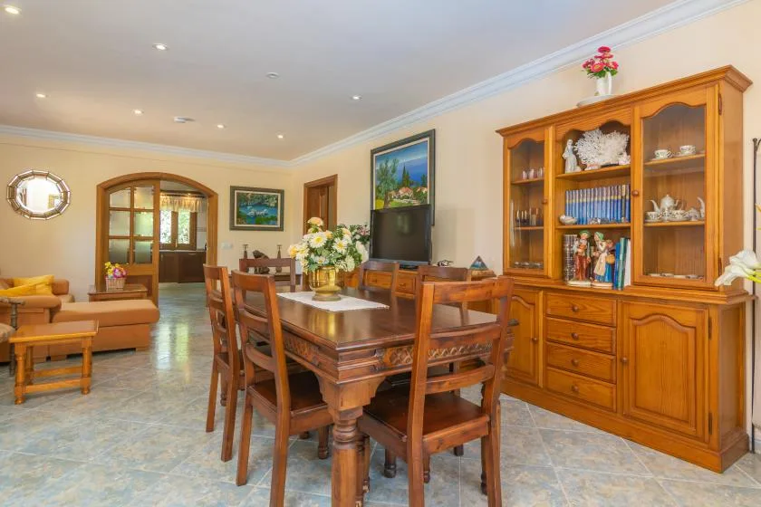 Un comedor y sala de estar con una mesa de madera y una vitrina.
