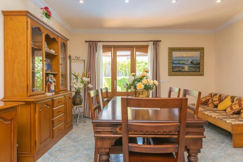 Un comedor con una mesa de madera y sillas junto a una ventana luminosa.