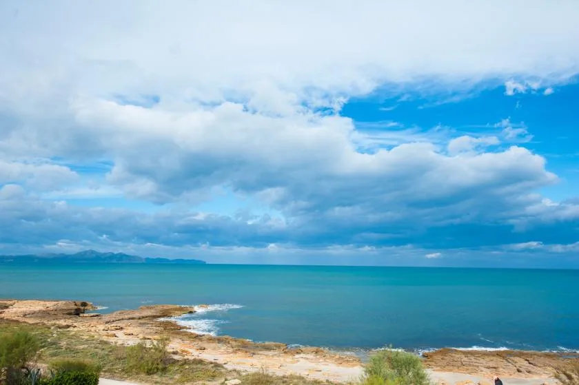 Un paisaje costero con agua turquesa bajo un cielo azul y nublado.