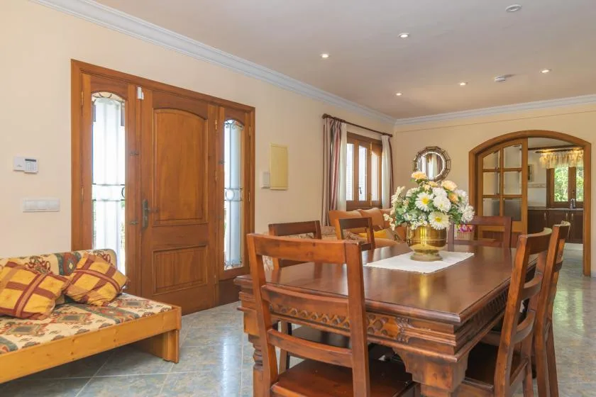Un comedor con una mesa y sillas de madera junto a una puerta de entrada de madera.
