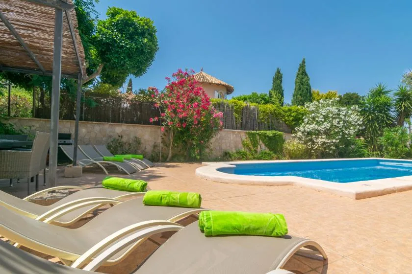 Zona de piscina al aire libre con tumbonas y toallas verdes.