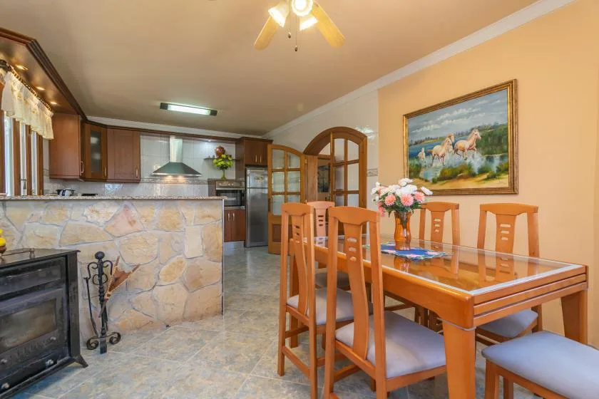 Comedor con mesa y sillas de madera junto a una cocina abierta.