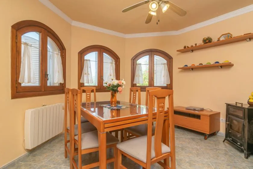 Un comedor con una mesa de madera bajo un ventilador de techo.