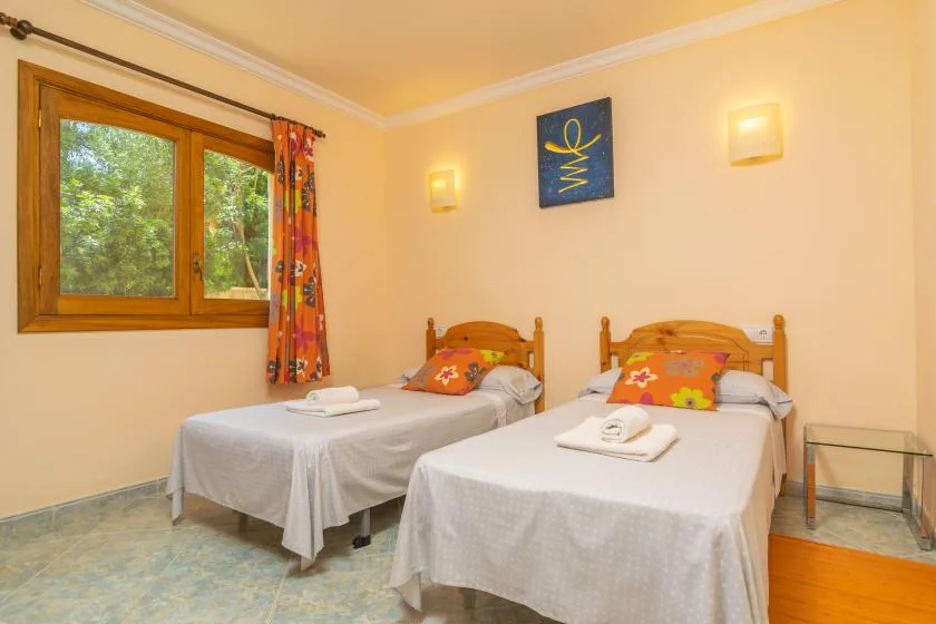 Un dormitorio con dos camas, una ventana y cortinas coloridas.