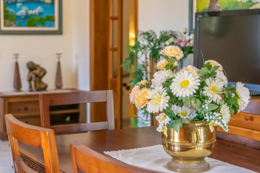 Una mesa de comedor tiene un arreglo floral frente a un televisor.