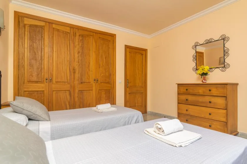 Un dormitorio con dos camas, armarios de madera y una cómoda con espejo.