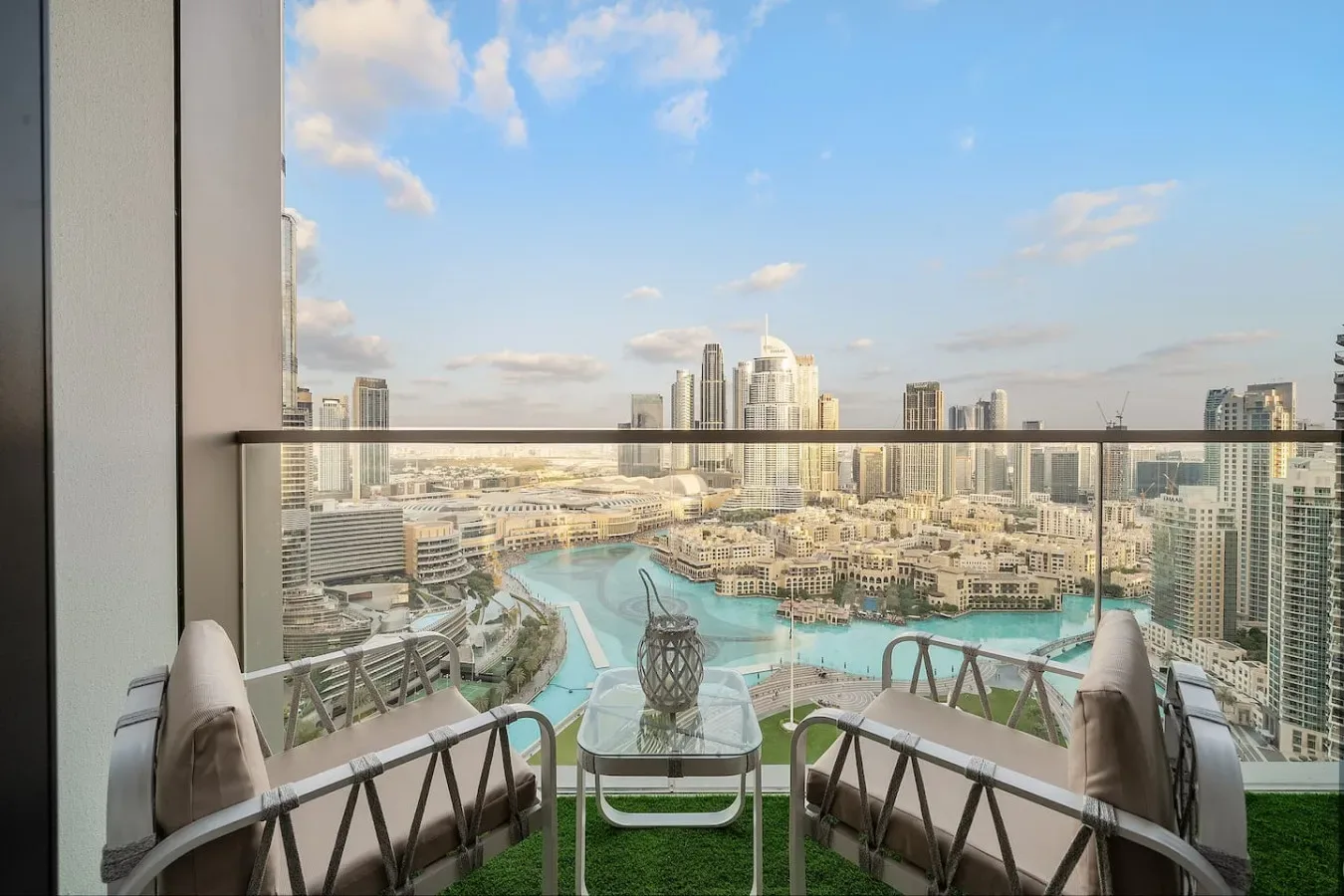 Una zona de estar en el balcón ofrece vistas a una piscina turquesa y al horizonte urbano.