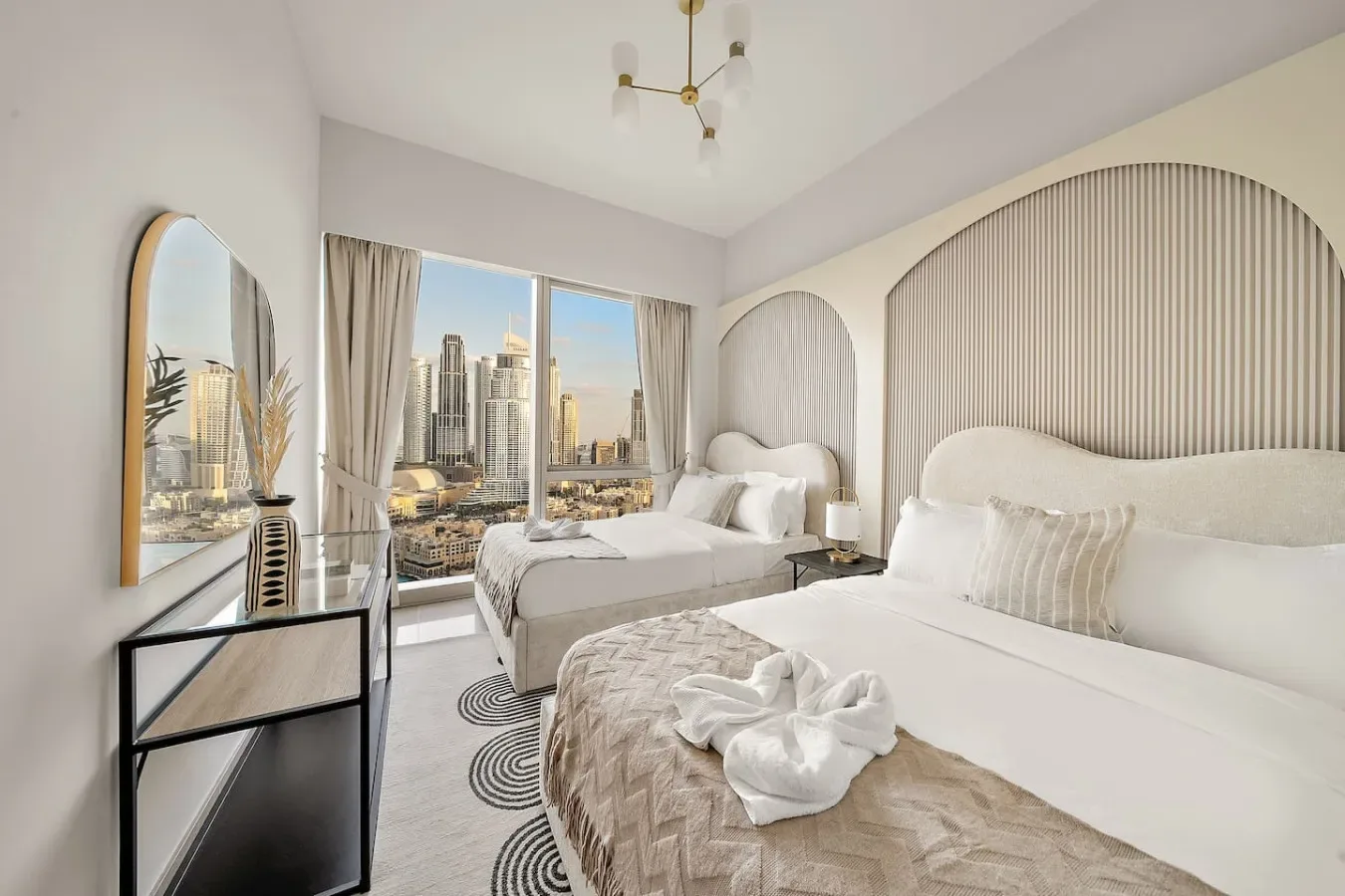 Un dormitorio con dos camas y grandes ventanas con vistas al perfil de la ciudad.