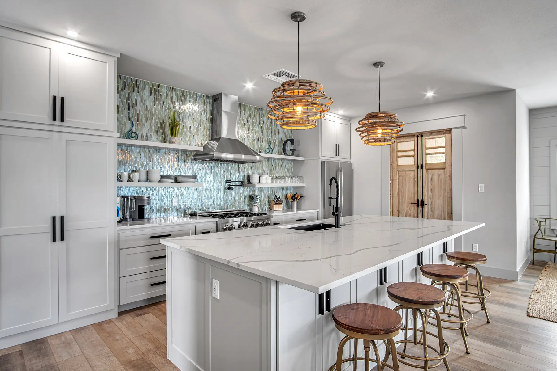 Una cocina luminosa cuenta con una gran isla con asientos y lámparas colgantes.