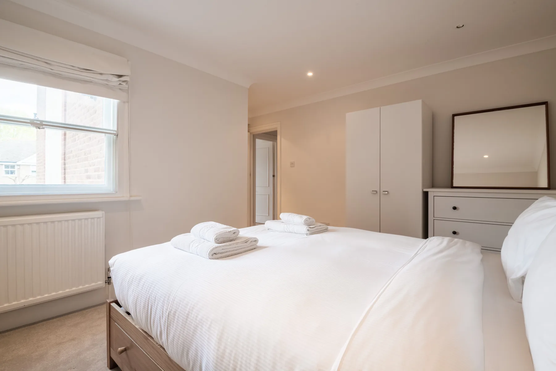A bright bedroom with a large bed and white bedding.