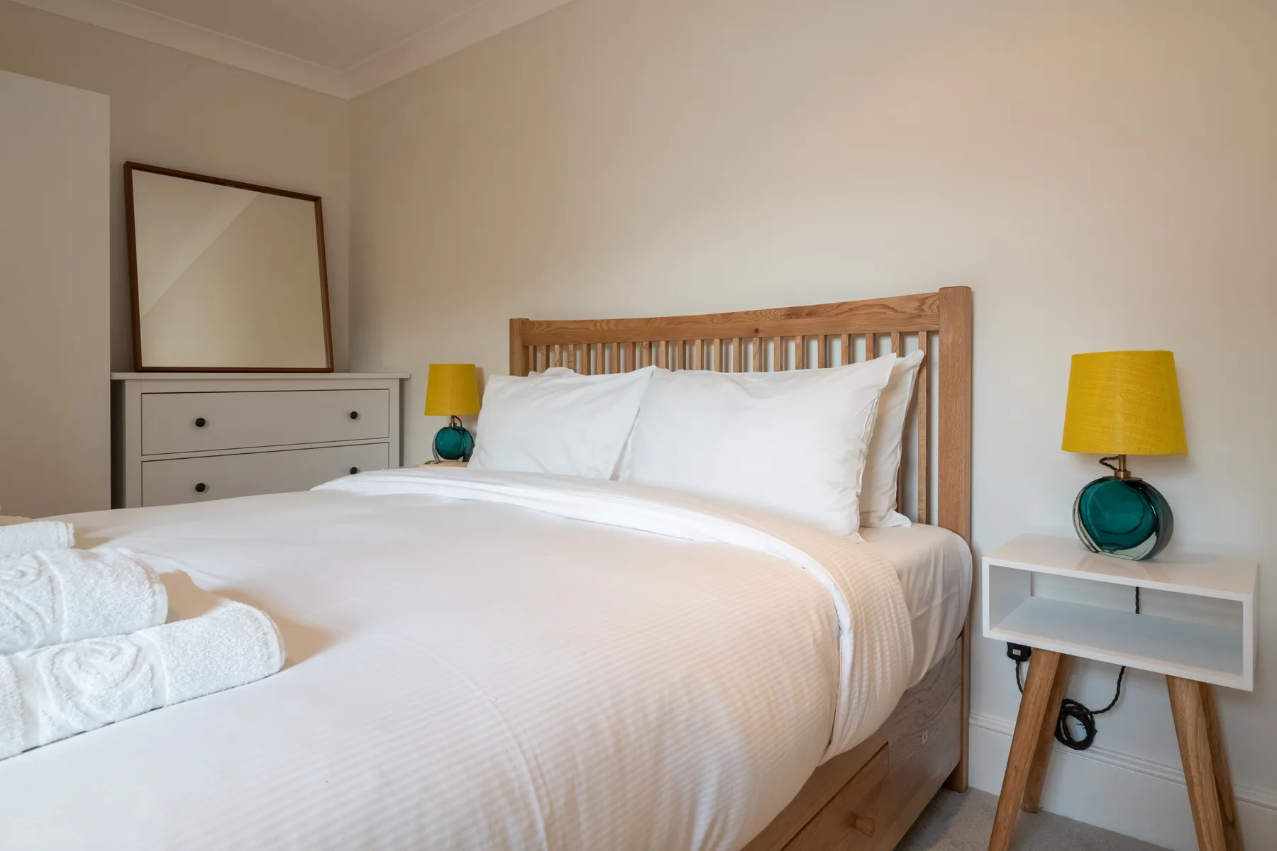 A bright bedroom with a neatly made bed and matching bedside lamps.