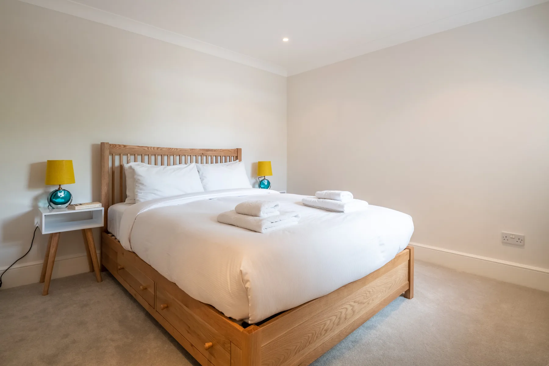 A bright bedroom with a neatly made bed and matching bedside tables.