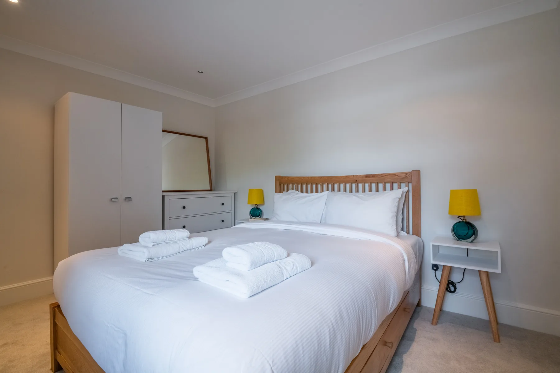 A bedroom with a neatly made bed and folded white towels.