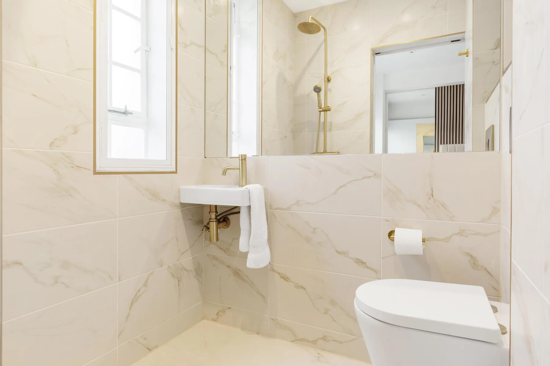 Un baño alicatado con lavabo suspendido y ducha.