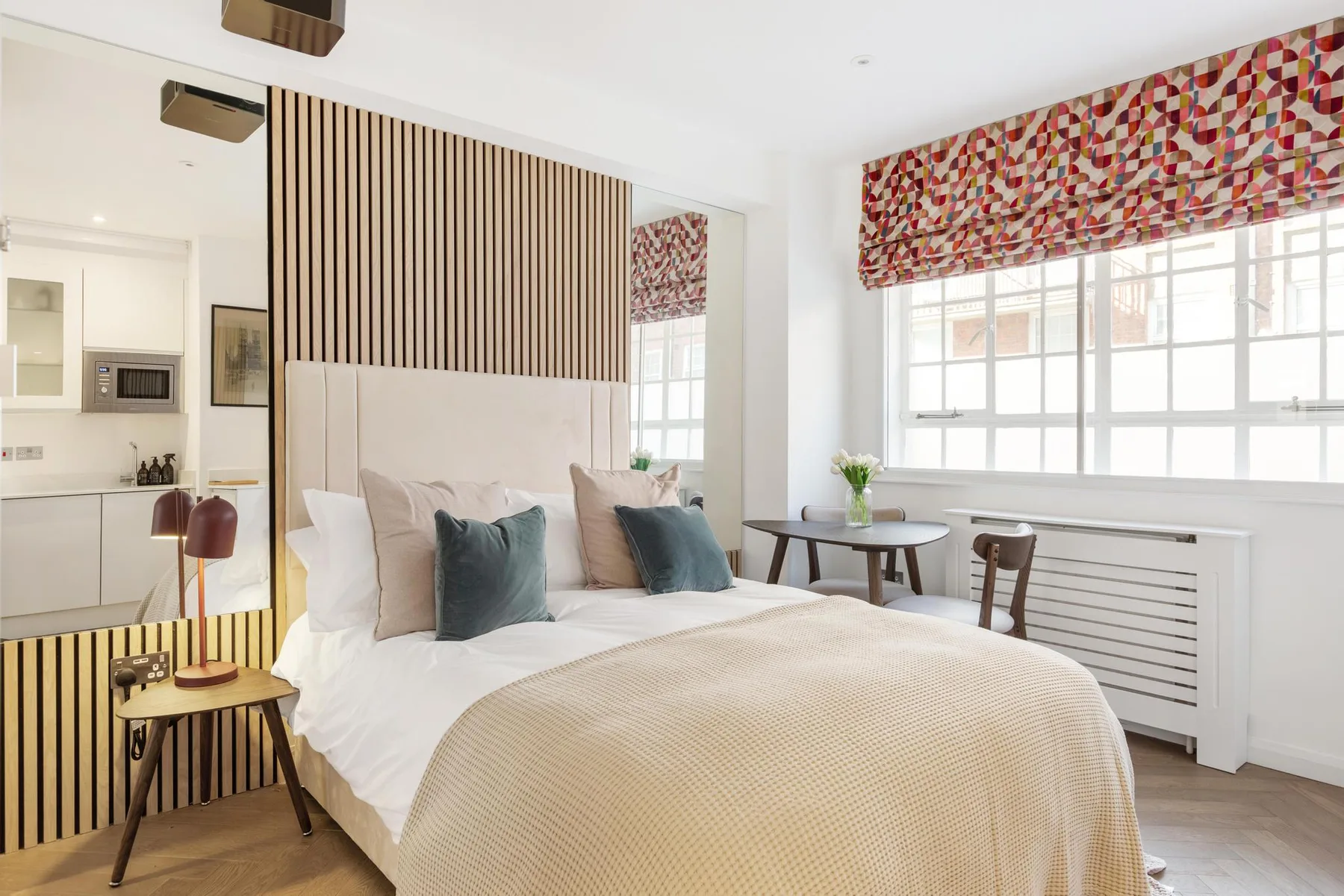 Un dormitorio luminoso con una cama grande y una mesa junto a la ventana.