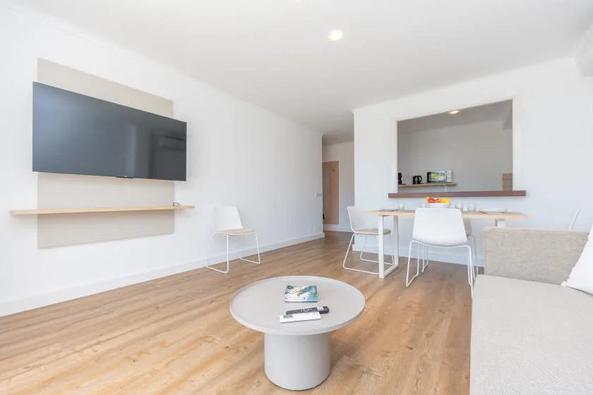 A bright living room with a television, seating, and a dining table.