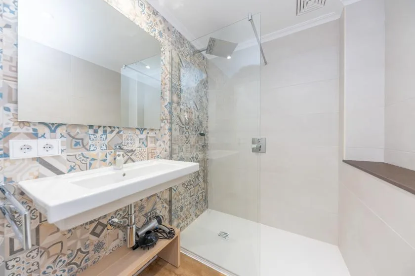 A bright bathroom with a sink beside a glass shower.