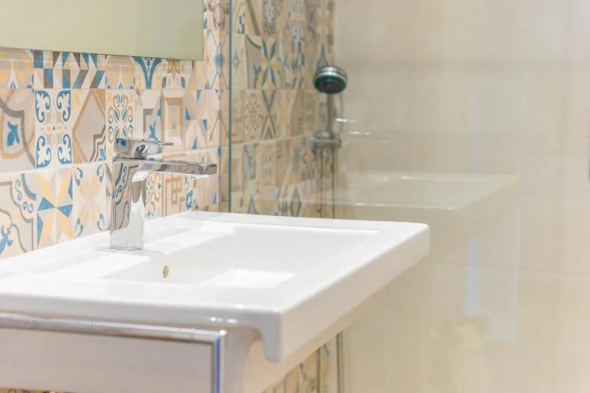 A bathroom vanity and sink stand beside a bathtub with a handheld shower.