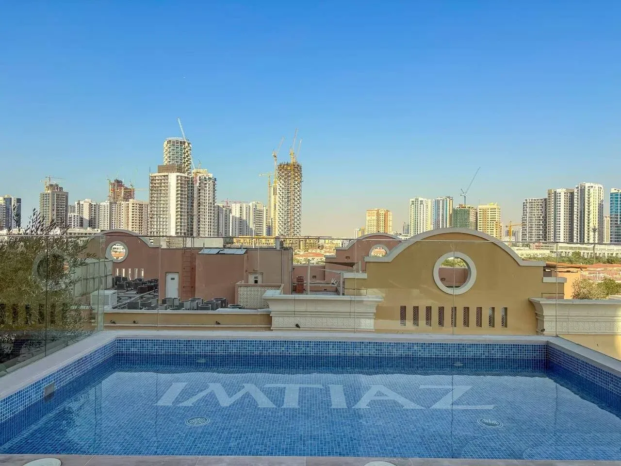 Una piscina en la azotea ofrece vistas del horizonte urbano bajo un cielo azul despejado.