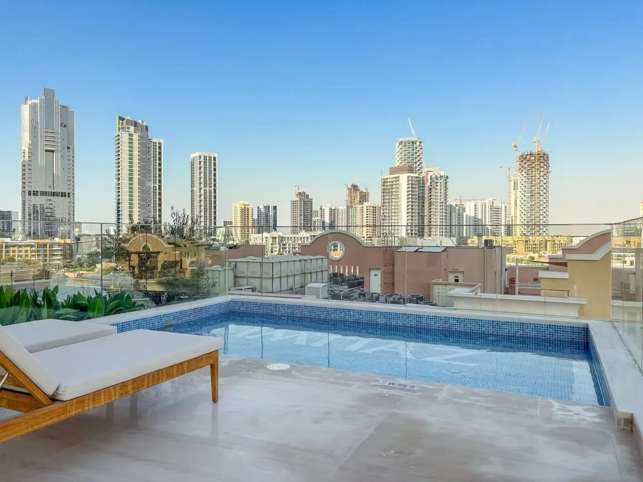 Una piscina en la azotea y asientos de descanso dan a un conjunto de edificios altos.