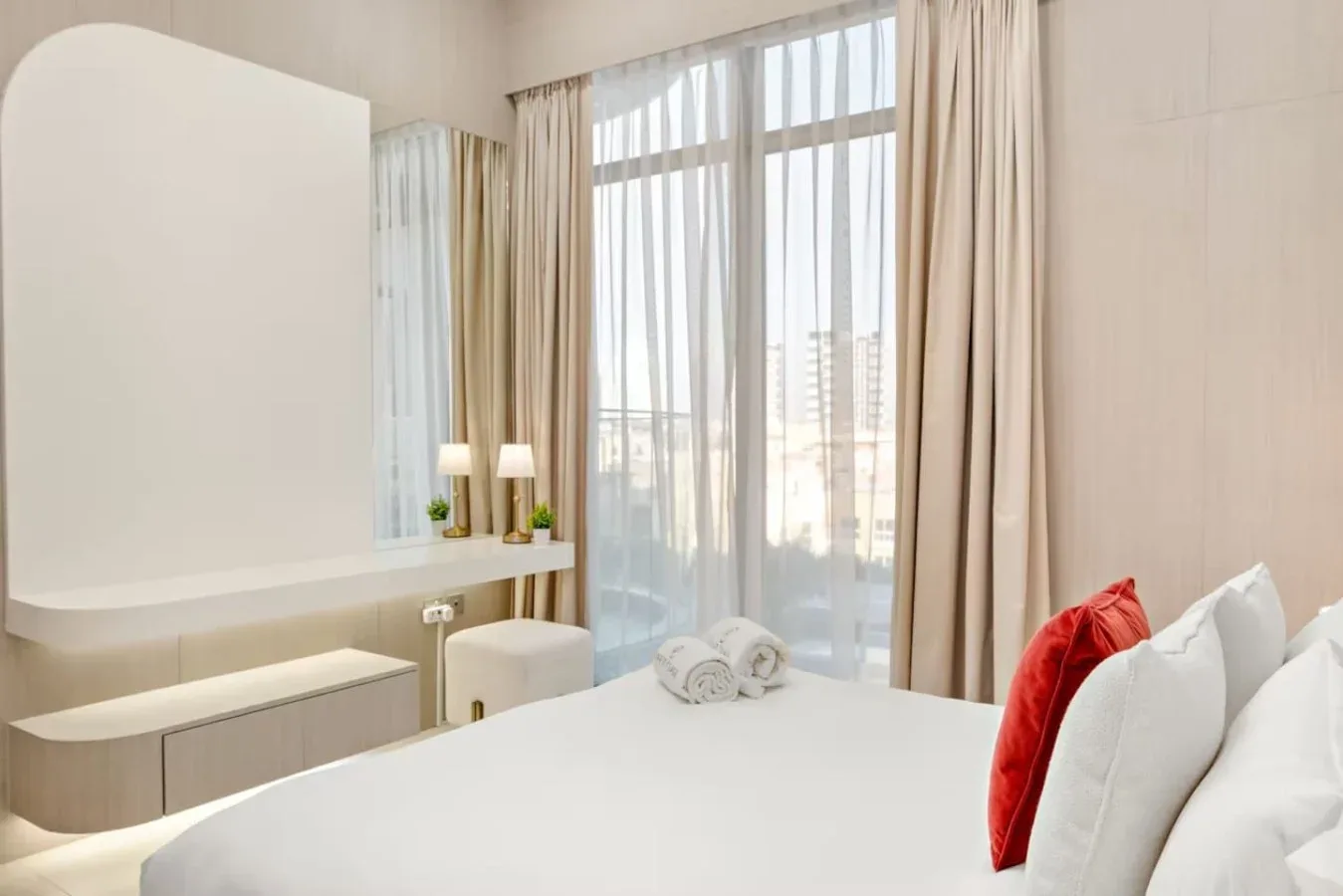 Un dormitorio luminoso con una cama junto a una gran ventana con cortinas.