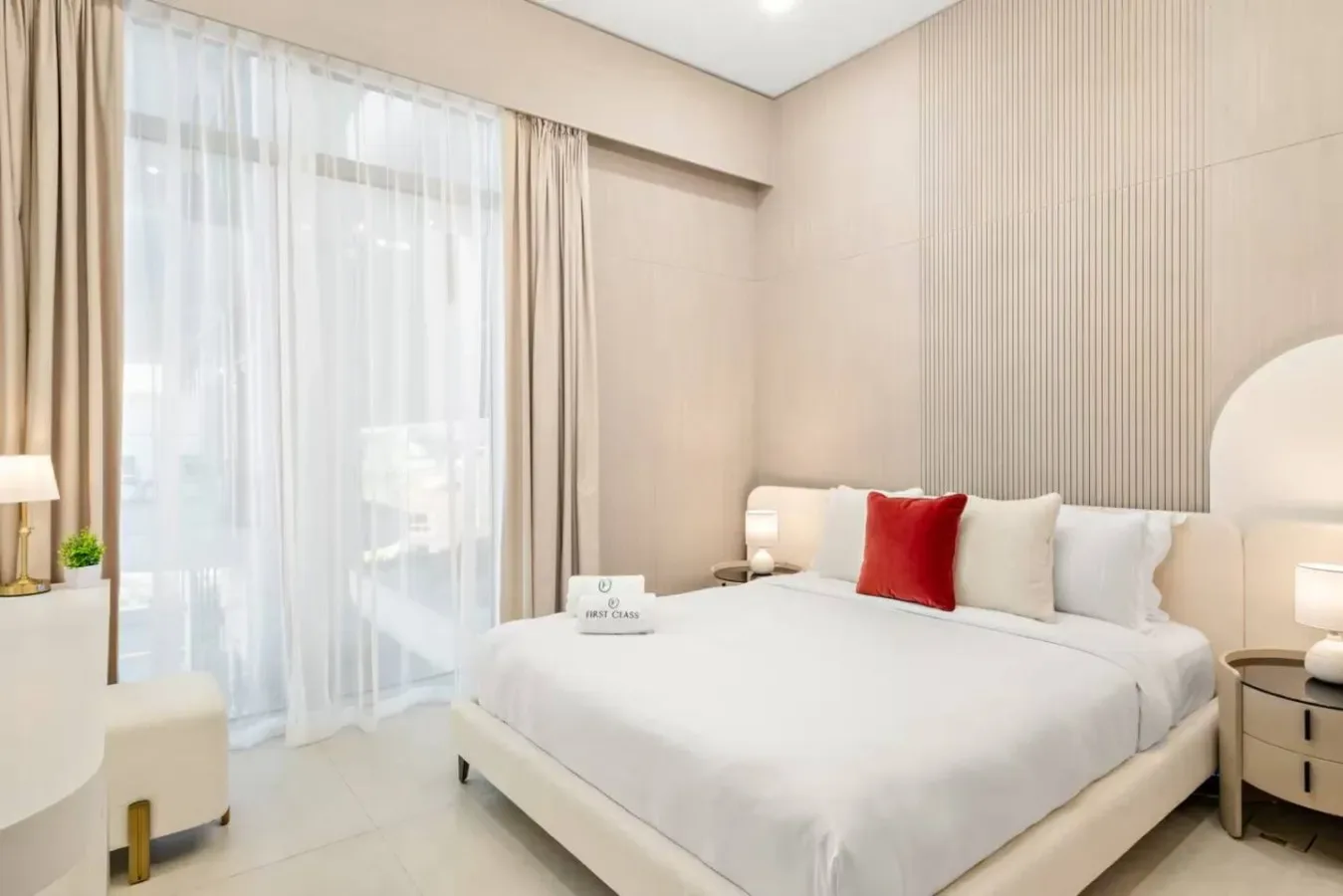 Un dormitorio luminoso con una cama grande y cortinas hasta el suelo.