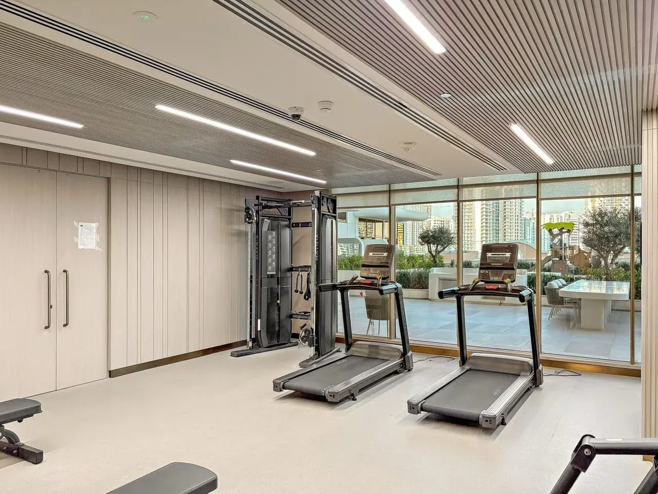Una luminosa sala de ejercicios con cintas de correr y equipo junto a grandes ventanales.