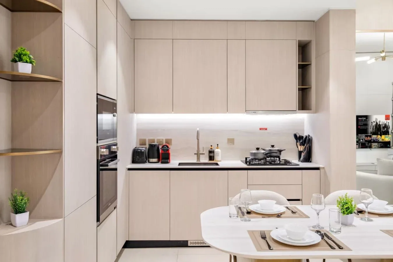 Una cocina moderna con gabinetes claros y una mesa de comedor puesta con platos.