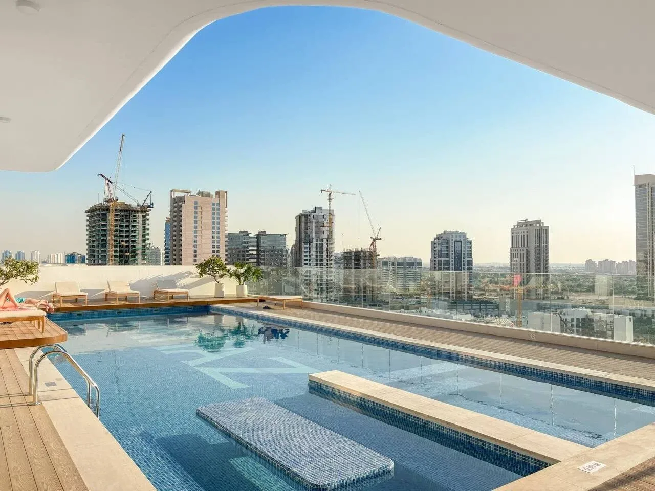 Una piscina en la azotea ofrece vistas del horizonte urbano bajo un cielo despejado.