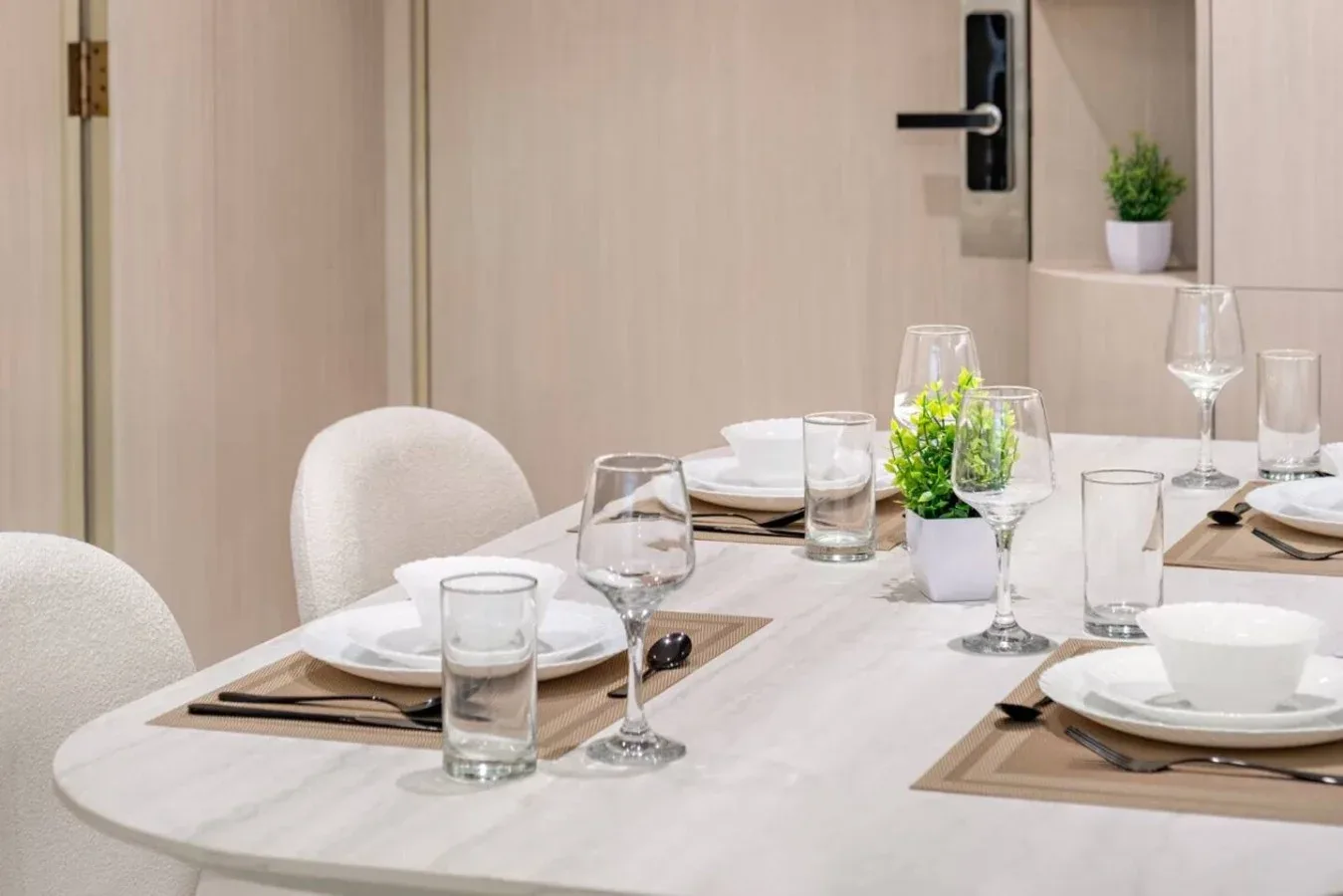 Comedor con una mesa puesta con platos, vasos y pequeñas plantas en macetas.