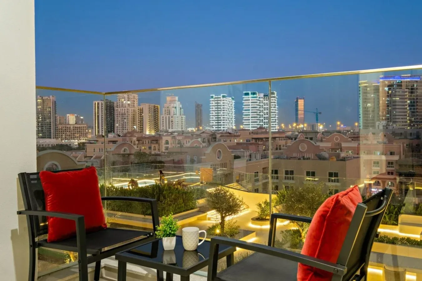 Una zona de asientos en un balcón da a edificios cercanos y al horizonte de la ciudad.