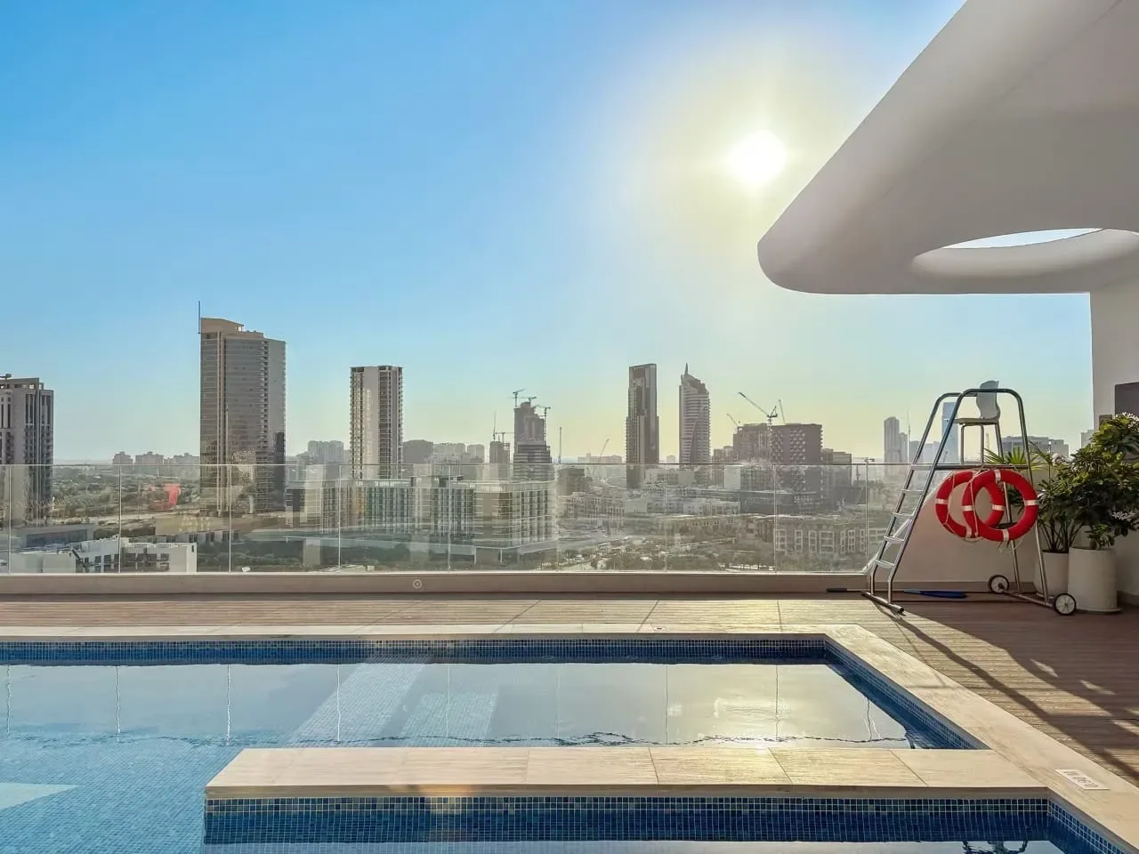 Una piscina en la azotea ofrece vistas del horizonte urbano bajo el sol.