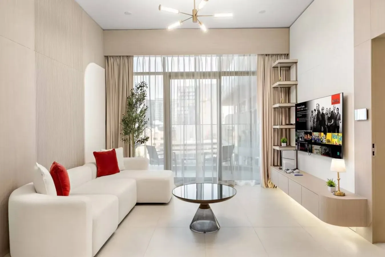 Una sala luminosa con asientos, una mesa de centro redonda y grandes ventanales con cortinas.