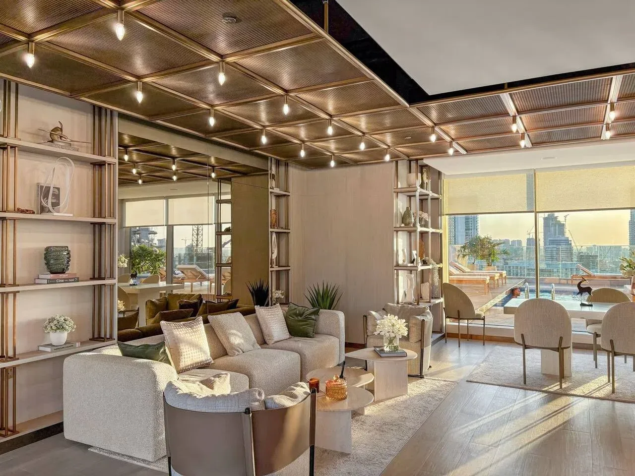 Una sala luminosa con asientos, estantes decorativos y grandes ventanas hacia una terraza.
