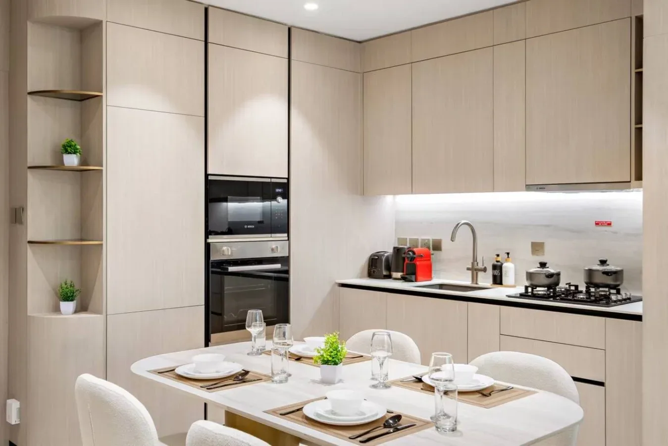 Cocina moderna y comedor con gabinetes claros y una mesa puesta.